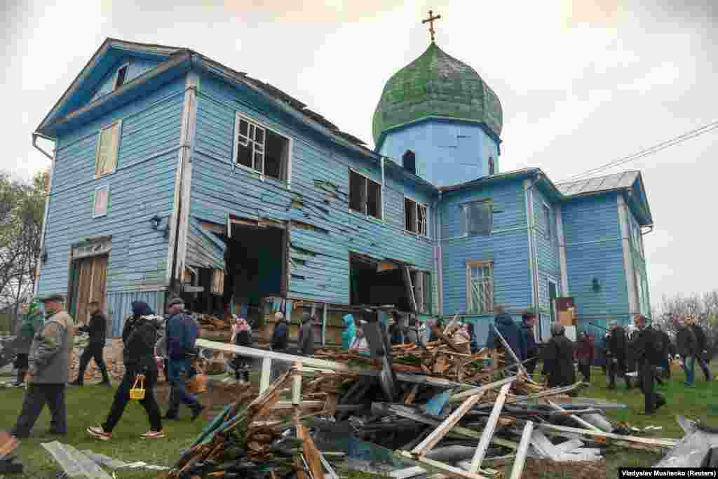 Місцеві жителі повертаються із Великоднього богослужіння, що проходило біля пошкодженої обстрілами церкви Різдва Пресвятої Богородиці. Селі Перемога, Київщина. 26 квітня 2022 року